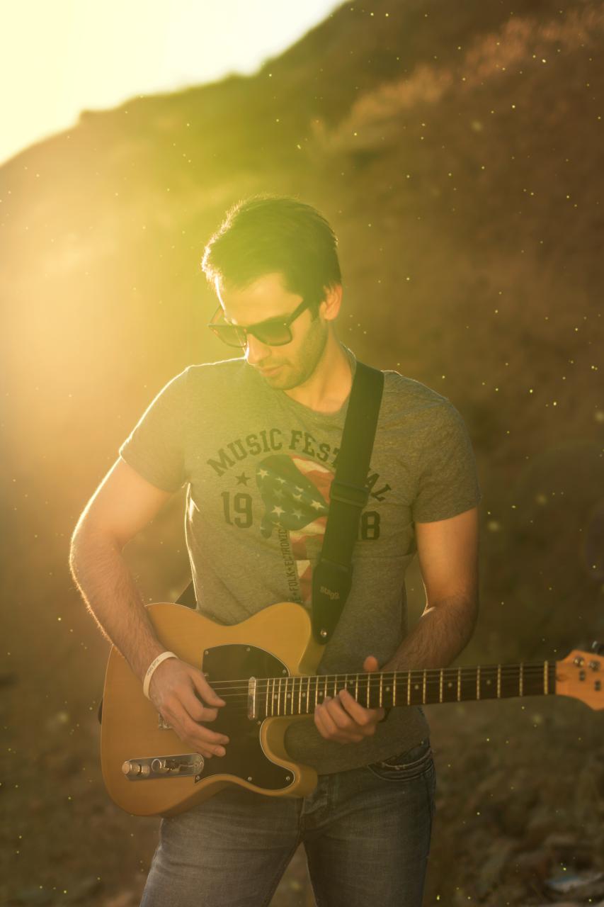 Man_playing_guitar_in_a_portrait_with_lens_flare.jpg